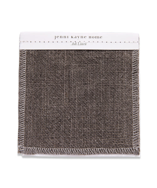 A square Fabric Swatch Ash Linen with visible white stitching and a textured, dark grayish-brown linen material designed to complement the Sunset Dining Arm Chair.