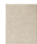 A close-up of the Palermo Rug’s corner shows its beige, textured linen wool surface with horizontal ridges. This sustainable rug feels soft underfoot and features a simple, minimalist design.