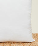 A close-up of the Linen Lumbar Pillow with a feather down insert sits on a textured beige mat, set against a neutral background.