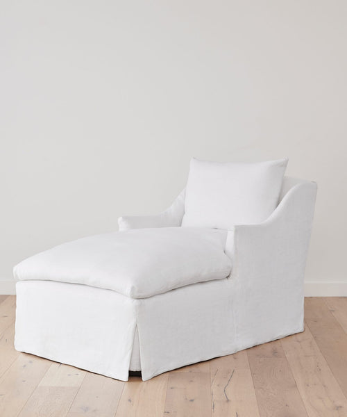 The Miramar Chaise features a cushioned seat, backrest, and armrests, set on a light wood floor against a white wall—bringing modern luxury and elegant comfort to any space.