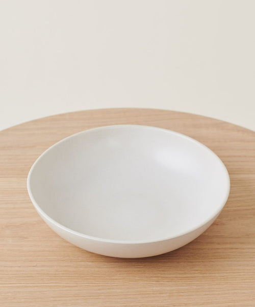 The Pacific Serving Bowl is displayed on a light wooden surface, viewed from above at a slight angle with a neutral background.