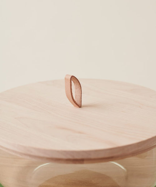 The Stowe Eco Glass Bowl features a round wooden lid with a leaf-shaped handle, crafted from FSC certified wood, making it a sustainable addition to your kitchen.