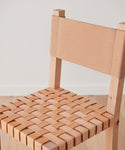 A close-up of the Tahoe Counter Stool shows its woven leather seat and solid leather backrest. The Knotty Alder wood frame contrasts against a plain white wall, while the stool stands on a light wood floor.