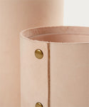 Close-up of the Small Leather Rivet Vase—a cylindrical, handmade piece featuring natural leather, raw edges, and brass rivets—set against a plain light background.