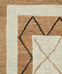 A close-up of three overlapping handwoven rugs in neutral tones highlights the Wilder Diamond Jute Rug, which features a bold black and brown diamond pattern on cream and tan with visibly rough, fibrous texture.