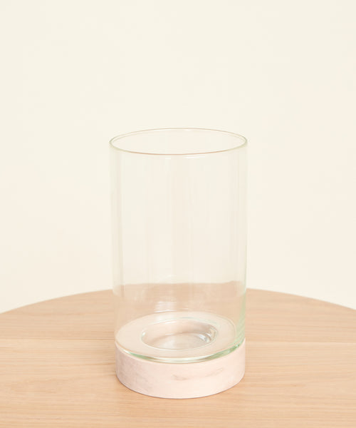The Stowe Eco Glass Vase, crafted from clear recycled glass with a slightly thicker base, sits on a round light wood table against a plain off-white background.