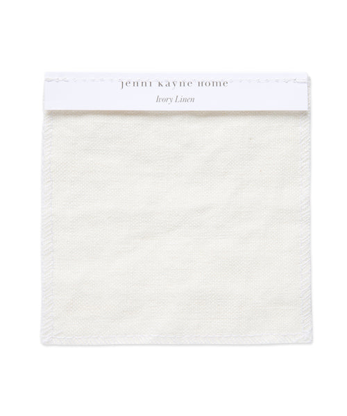 The Fabric Swatch Ivory Linen is a square sample of subtly textured ivory Belgian flax linen, neatly hemmed, with a white label at the top reading jenni kayne home and Ivory Linen in light gray.