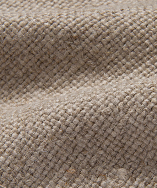 Close-up of the Miramar Chaise Slipcovers textured beige burlap fabric, highlighting its coarse woven fibers, small knots, and natural folds—reminiscent of the organic texture found in flax linen.