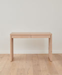 The Newport Desk is a minimalist solid wood piece with clean lines and two drawers, shown against a plain white wall on a matching wooden floor.