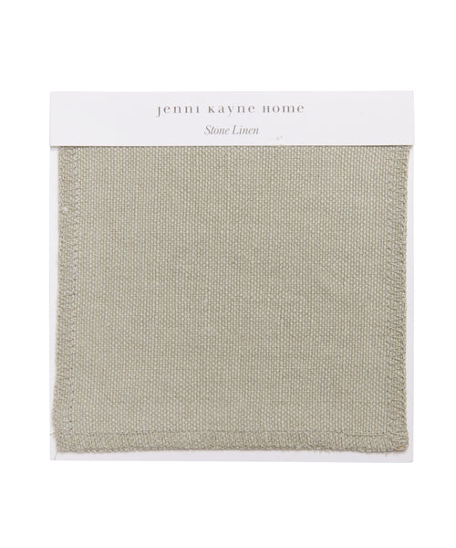 The Fabric Swatch Stone Linen is a square, light stone-gray sample with a visible woven texture and stitched edges, mounted on a white card labeled jenni kayne home and Stone Linen—ideal for the Pacific Bed.