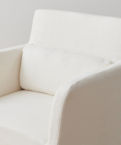 A close-up of the Sunset Dining Arm Chair Slipcover, shown in modern off-white alabaster linen with a matching cushion, set against a plain background.