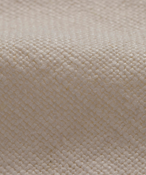 Close-up of the Sunset Dining Arm Chair Slipcover in textured off-white alabaster linen, featuring a grid-like pattern and soft folds that highlight the natural fibers—ideal for adding an elegant touch to your dining space.