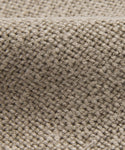 Close-up of the Sunset Dining Chair Slipcover in beige woven fabric. Its coarse, textured pattern and gentle folds add subtle elegance—perfect for enhancing any dining chair with a taupe linen look.
